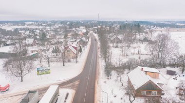 Akniste, Jekabpils, Letonya, Baltık. Kışın insansız hava aracından Akniste şehrine kadar uzanan güzel panoramik hava manzaralı fotoğraf. Küçük kasaba ve ormanlarda kar yağışlı bir kış manzarası. (seri)