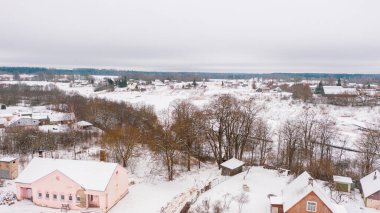 Akniste, Jekabpils, Letonya, Baltık. Kışın insansız hava aracından Akniste şehrine kadar uzanan güzel panoramik hava manzaralı fotoğraf. Küçük kasaba ve ormanlarda kar yağışlı bir kış manzarası. (seri)