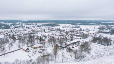 Akniste, Jekabpils, Letonya, Baltık. Kışın insansız hava aracından Akniste şehrine kadar uzanan güzel panoramik hava manzaralı fotoğraf. Küçük kasaba ve ormanlarda kar yağışlı bir kış manzarası. (seri)