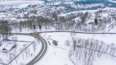 Akniste, Jekabpils, Letonya, Baltık. Kışın insansız hava aracından Akniste şehrine kadar uzanan güzel panoramik hava manzaralı fotoğraf. Küçük kasaba ve ormanlarda kar yağışlı bir kış manzarası. (seri)
