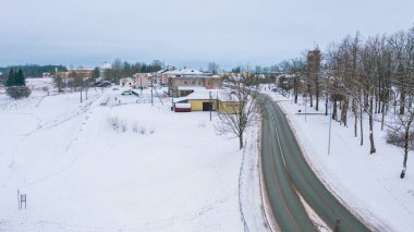 Akniste, Jekabpils, Letonya, Baltık. Kışın insansız hava aracından Akniste şehrine kadar uzanan güzel panoramik hava manzaralı fotoğraf. Küçük kasaba ve ormanlarda kar yağışlı bir kış manzarası. (seri)