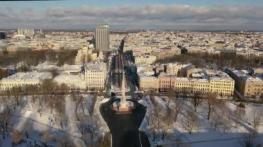 Riga, Letonya, Baltık. Karlı, güneşli bir kış gününde Letonya Özgürlük Anıtı 'yla Özgürlük Meydanı' na insansız hava aracından gelen güzel panoramik 4K videosu..