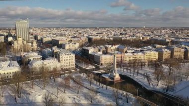 Riga, Letonya, Baltık. Karlı, güneşli bir kış gününde Letonya Özgürlük Anıtı 'yla Özgürlük Meydanı' na insansız hava aracından gelen güzel panoramik 4K videosu..