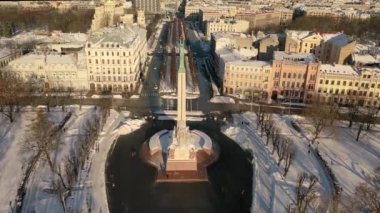 Riga, Letonya, Baltık. Karlı, güneşli bir kış gününde Letonya Özgürlük Anıtı 'yla Özgürlük Meydanı' na insansız hava aracından gelen güzel panoramik 4K videosu..