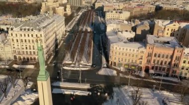 Riga, Letonya, Baltık. Karlı, güneşli bir kış gününde Letonya Özgürlük Anıtı 'yla Özgürlük Meydanı' na insansız hava aracından gelen güzel panoramik 4K videosu..