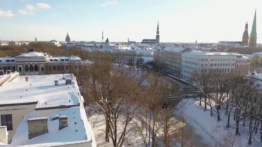 Riga, Letonya, Baltık. Güzel bir kış gününde Riga St. Peter Kilisesi ve Kubbesi 'nin arka planında İHA' dan Old Riga 'ya güzel panoramik hava 4K videosu açılıyor. (seri)