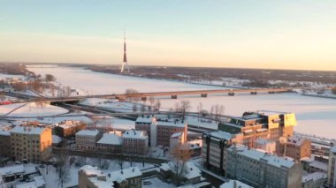 Riga, Letonya, Baltık. Uçan İHA 'dan hareket eden makinelerle Ada Köprüsü' ne, kış günbatımından güzel panoramik 4K video. (Seriler)