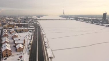 Riga, Letonya, Baltık. Güneşli bir kış gününde Daugava Nehri 'nin arka planında ve şehir merkezinde Ada Köprüsü' nde insansız hava aracı uçururken çekilen güzel panoramik 4K videosu. (Seriler)