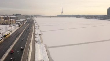 Riga, Letonya, Baltık. Güneşli bir kış gününde Daugava Nehri 'nin arka planında ve şehir merkezinde Ada Köprüsü' nde insansız hava aracı uçururken çekilen güzel panoramik 4K videosu. (Seriler)