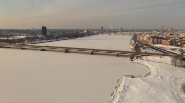 Riga, Letonya, Baltık. Güneşli bir kış gününde Daugava Nehri 'nin arka planında ve şehir merkezinde Ada Köprüsü' nde insansız hava aracı uçururken çekilen güzel panoramik 4K videosu. (Seriler)