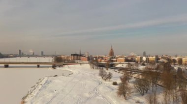Riga, Letonya, Baltık. Güneşli bir kış gününde Daugava Nehri 'nin arka planında ve şehir merkezinde Ada Köprüsü' nde insansız hava aracı uçururken çekilen güzel panoramik 4K videosu. (Seriler)