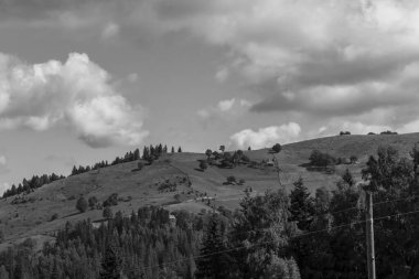 Bir dağ manzarasının siyah ve beyaz fotoğrafı, güneşli bir günde bulutlu mavi gökyüzü