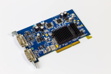 Beyaz arkaplandaki mavi bilgisayar grafik kartının açılı görüntüsü. Siyah bir ısıtıcı, çeşitli kapasitörler, mikroçipler ve çift DVI çıkış portlarına sahiptir..