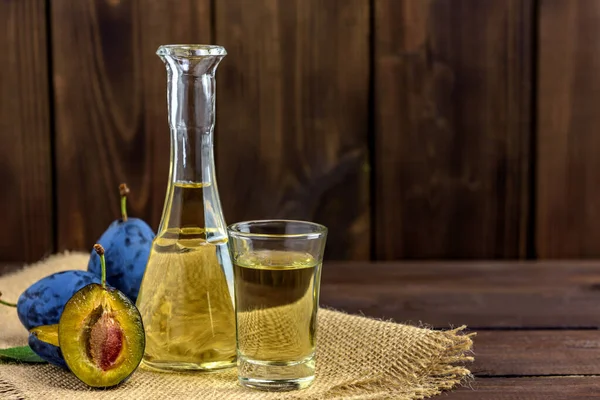 Erik brendisi ya da bardakta schnapps ve ahşap bir masada taze erikler ve metin için fotokopi alanı. Seçici odak.