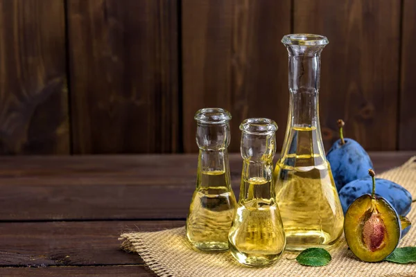 Küçük cam şişelerde erik brendisi ya da schnapps. Taze ve lezzetli erikler ahşap bir masada, metin için fotokopi alanı var. Seçici odak.