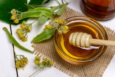Cam kasede bal, ıhlamur balı ve ahşap bir masada taze ıhlamur çiçeği. Seçici odak.