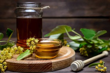 Kavanoz ve ıhlamur balı bal ve bal için sopa ve ahşap bir masada taze ıhlamur çiçeği..