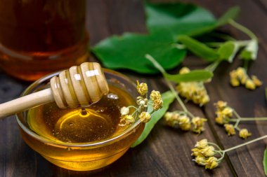 Cam kasede bal, ıhlamur balı ve ahşap bir masada taze ıhlamur çiçeği. Seçici odak.