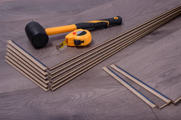 Kaplama paneller üzerinde çekiç ve mezura, odaya lamine koymak için marangoz araçları.  