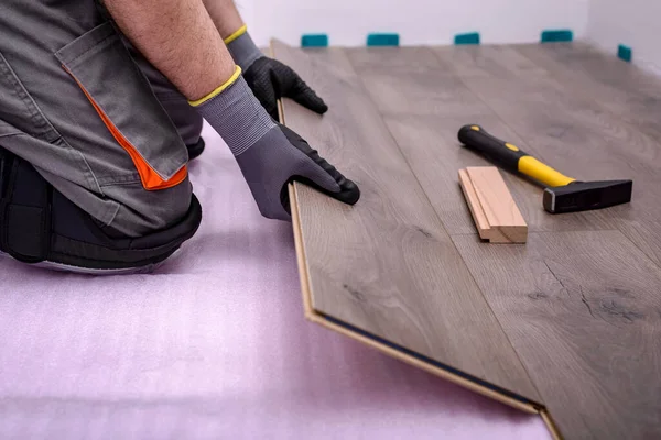 Erkek eller, odanın zeminine ahşap kaplama döşeme döşüyorlar. Seçici odak.