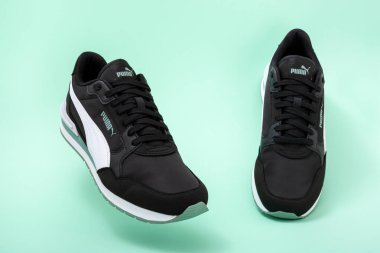 Obrenovac, Sırbistan - 10 Temmuz 2025: Açık yeşil arka planda şık siyah Puma ayakkabıları.