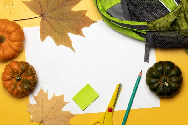 Backpack, school supplies, orange leaves and pumpkins on yellow background. Greeting card for Teachers Day