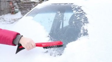 kadın kırmızı ceketli bir araba penceresinden kar temizlemek için.