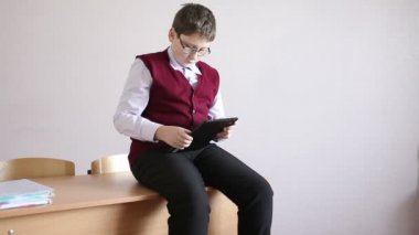 sınıfta masaya oturan tablet oynayan çocuk