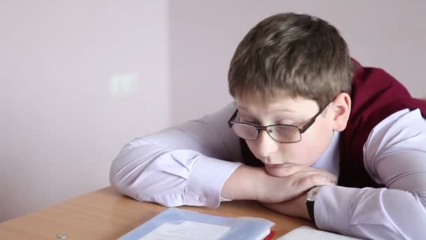 Trauriger Junge mit Brille sitzt im Klassenzimmer — Stockvideo