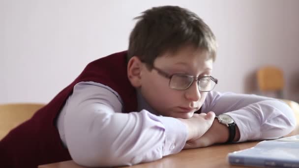 Trauriger Junge mit Brille sitzt im Seitenprofil eines Klassenzimmers — Stockvideo