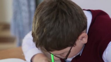 gözlüklü çocuk masa başında oturan bir not defterinde yazıyor