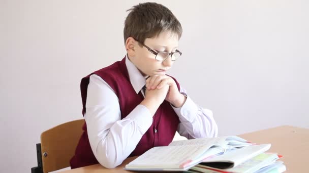 Boy with glasses reading a book and rubs his eyes hands — Stock Video