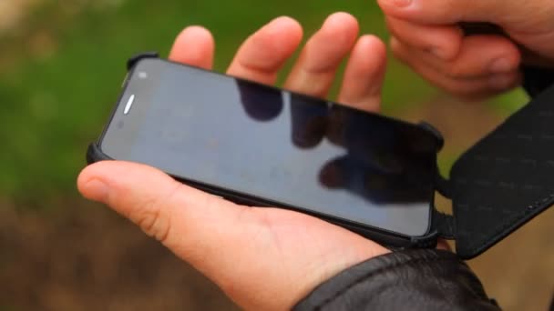 Mężczyzna otwiera przypadku smartphone i używa go — Wideo stockowe