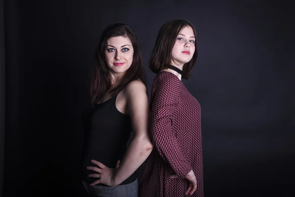 Portrait of mother and daughter in the studio on a dark backgrou — Stock Photo, Image