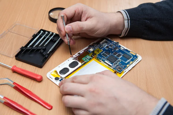 Master repairs the tablet computer. Top view of hands working. — Stock Photo, Image