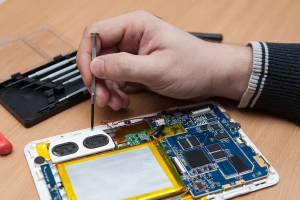 Master repairs the tablet computer. Top view of hands working. — Stock Photo, Image