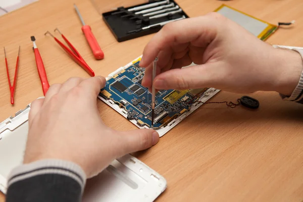 Master repairs the tablet computer. Top view of hands working. — Stock Photo, Image