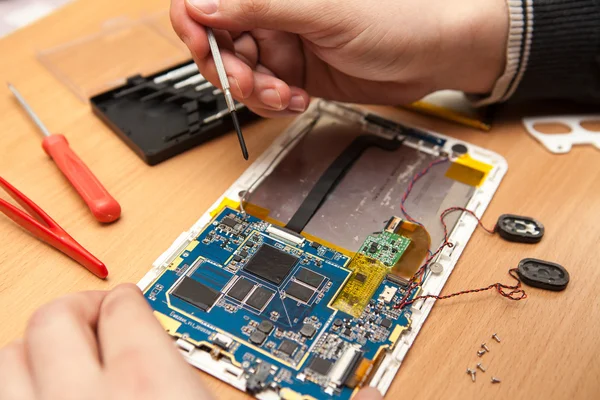 Master repairs the tablet computer. Top view of hands working. — Stock Photo, Image