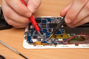 Master zarar için bir multimetre kullanarak tablet arıyor.