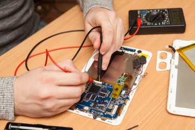 Master zarar için bir multimetre kullanarak tablet arıyor.