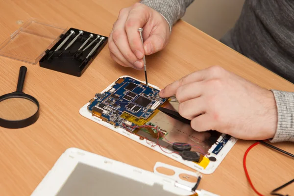 Wizard parses the tablet computer. Hands with a screwdriver. — Stock Photo, Image