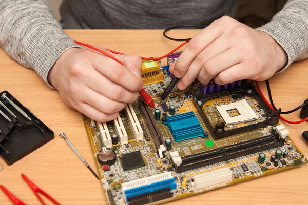 Meester zoekt de schuld van het moederbord met een multim — Stockfoto