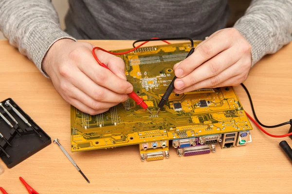 Meester zoekt de schuld van het moederbord met een multim — Stockfoto