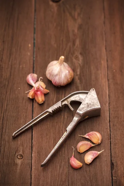 Schiacciapasta per aglio e aglio su fondo di legno — Foto Stock