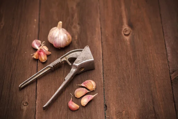 Schiacciapasta per aglio e aglio su fondo di legno — Foto Stock