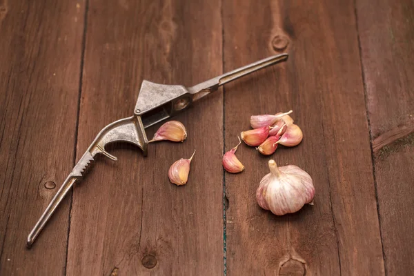 Schiacciapasta per aglio e aglio su fondo di legno — Foto Stock