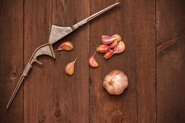 Masher for garlic and garlic on a wooden background — Stock Photo, Image