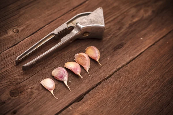 Masher for garlic and garlic on a wooden background — Stock Photo, Image