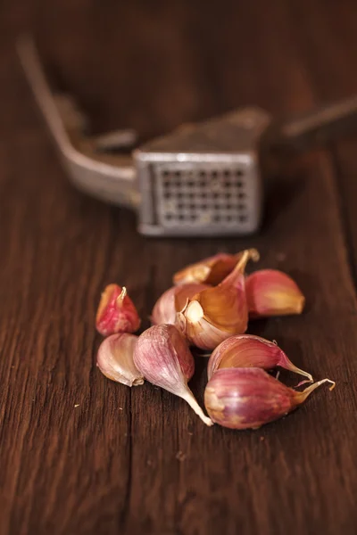 Schiacciapasta per aglio e aglio su fondo di legno — Foto Stock