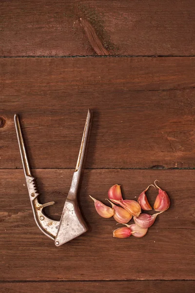 Машер для чеснока и чеснока на деревянном фоне — стоковое фото
